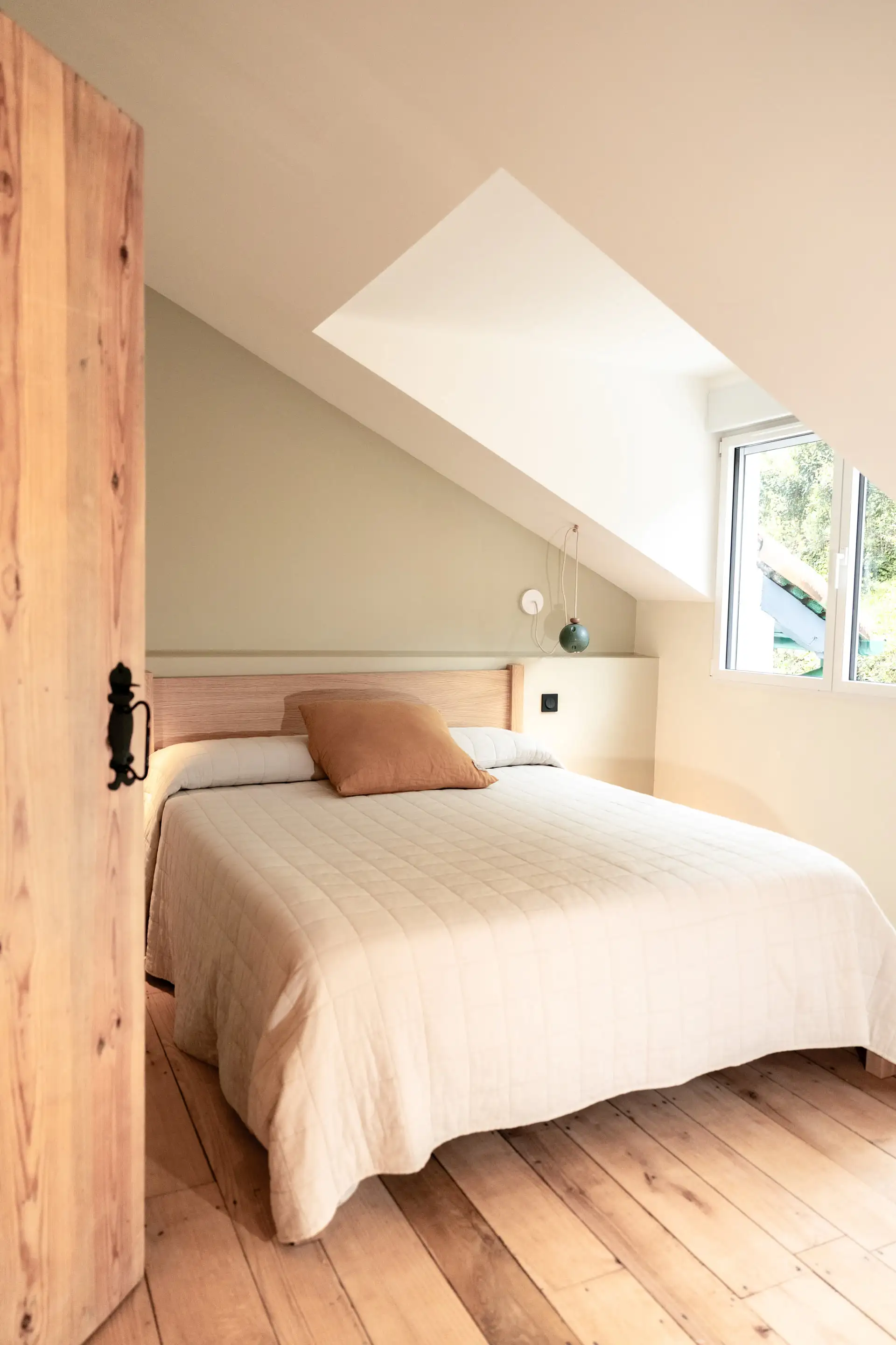 Chambre avec porte en bois brut et lit fait de blanc
