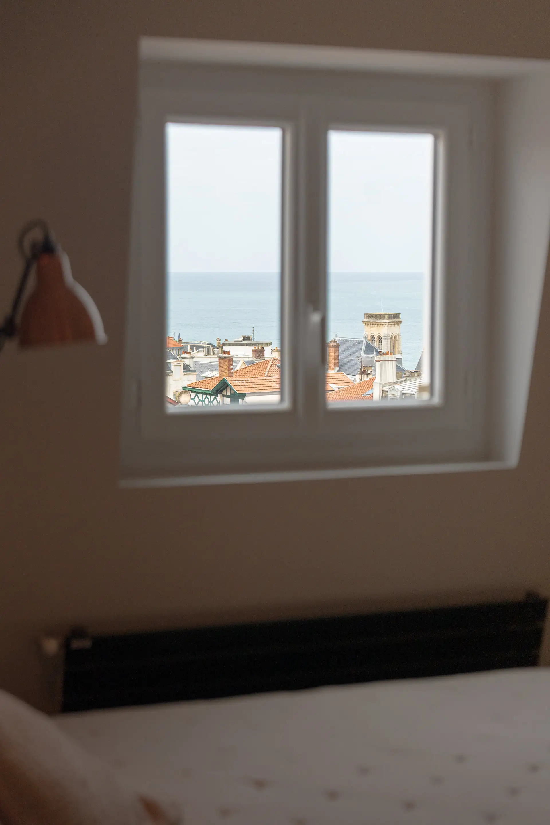 Fenêtre de la chambre ouverte sur les toits et l’océan