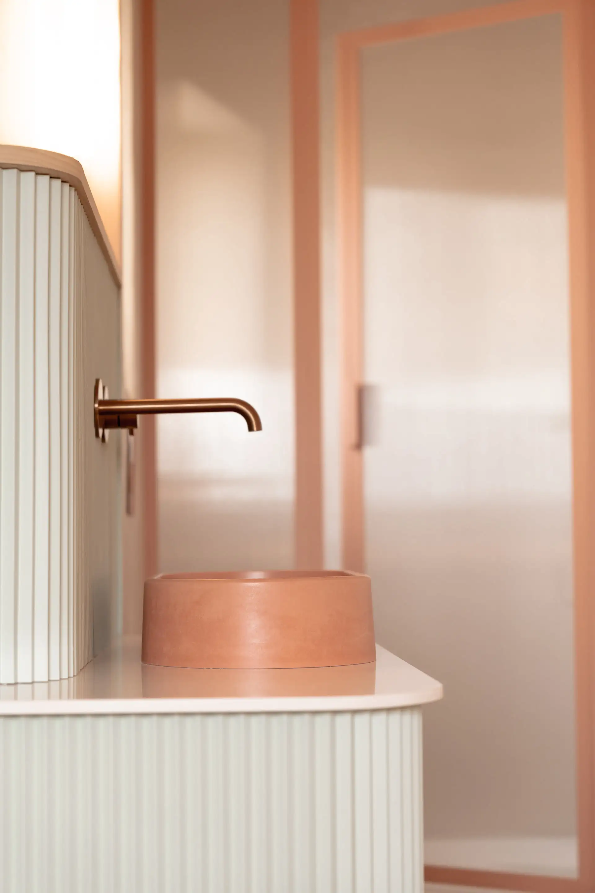 Vasque rose sur un meuble cannelé vert sauge