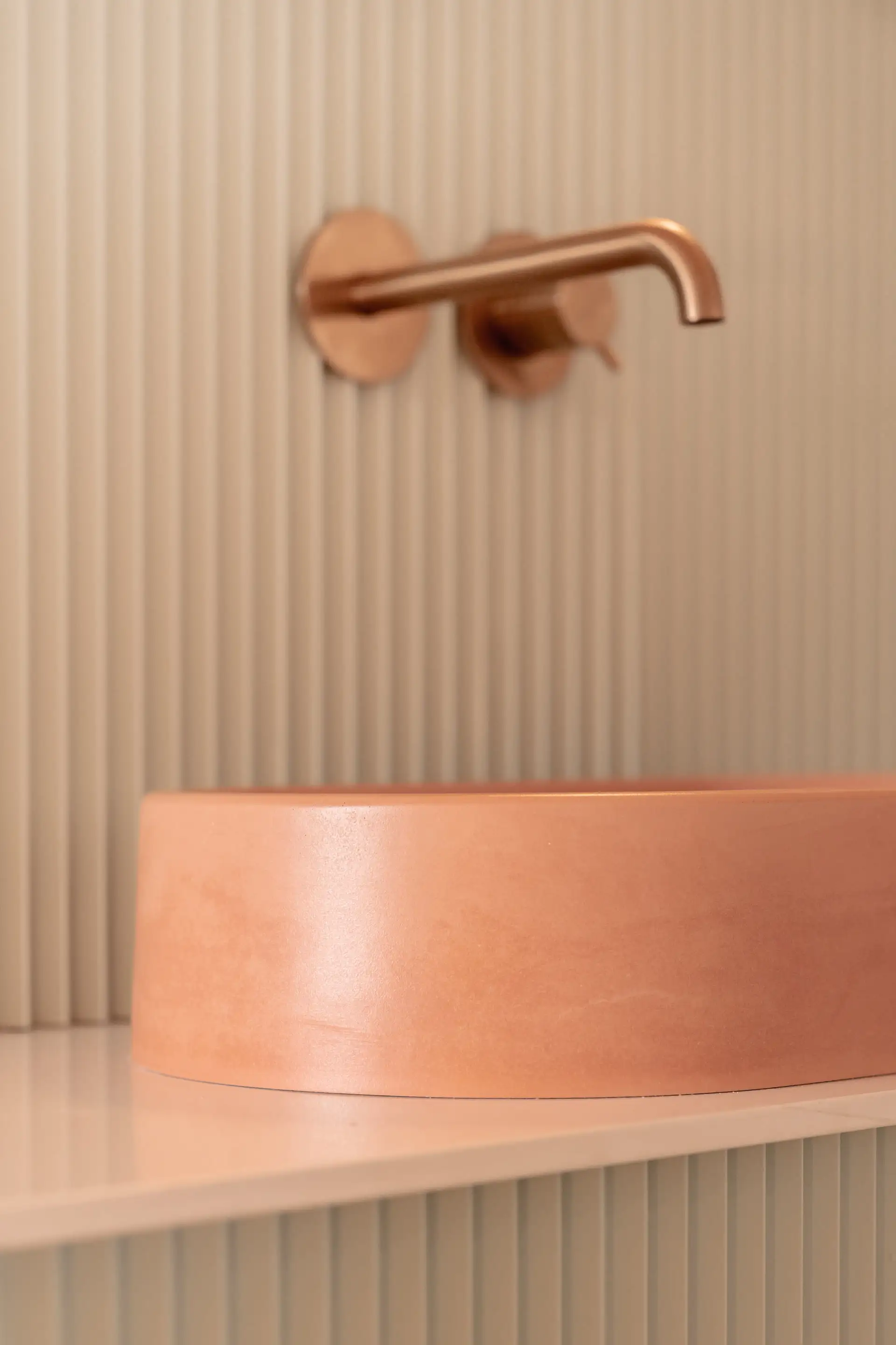 Robinet en cuivre au-dessus d’une vasque rose