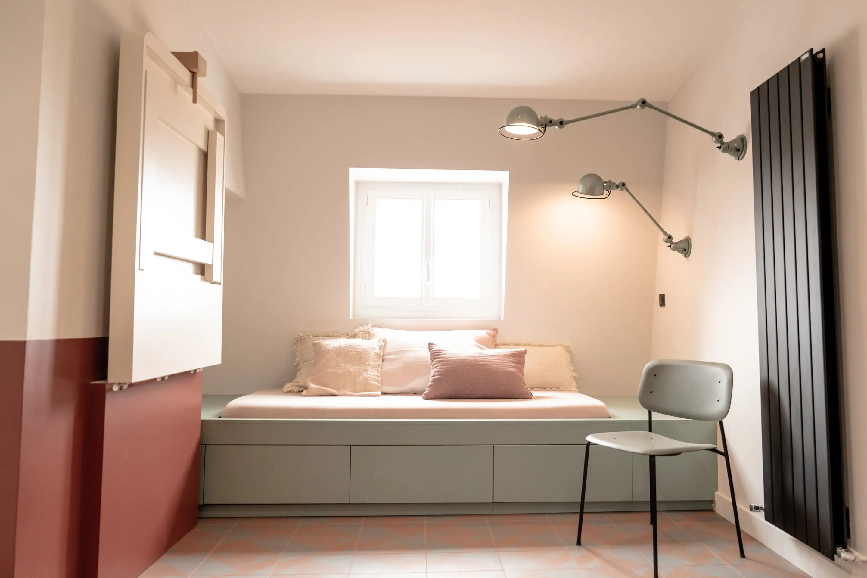 Pièce de vie sous les combles, banquette-lit vert sauge et mur terracotta