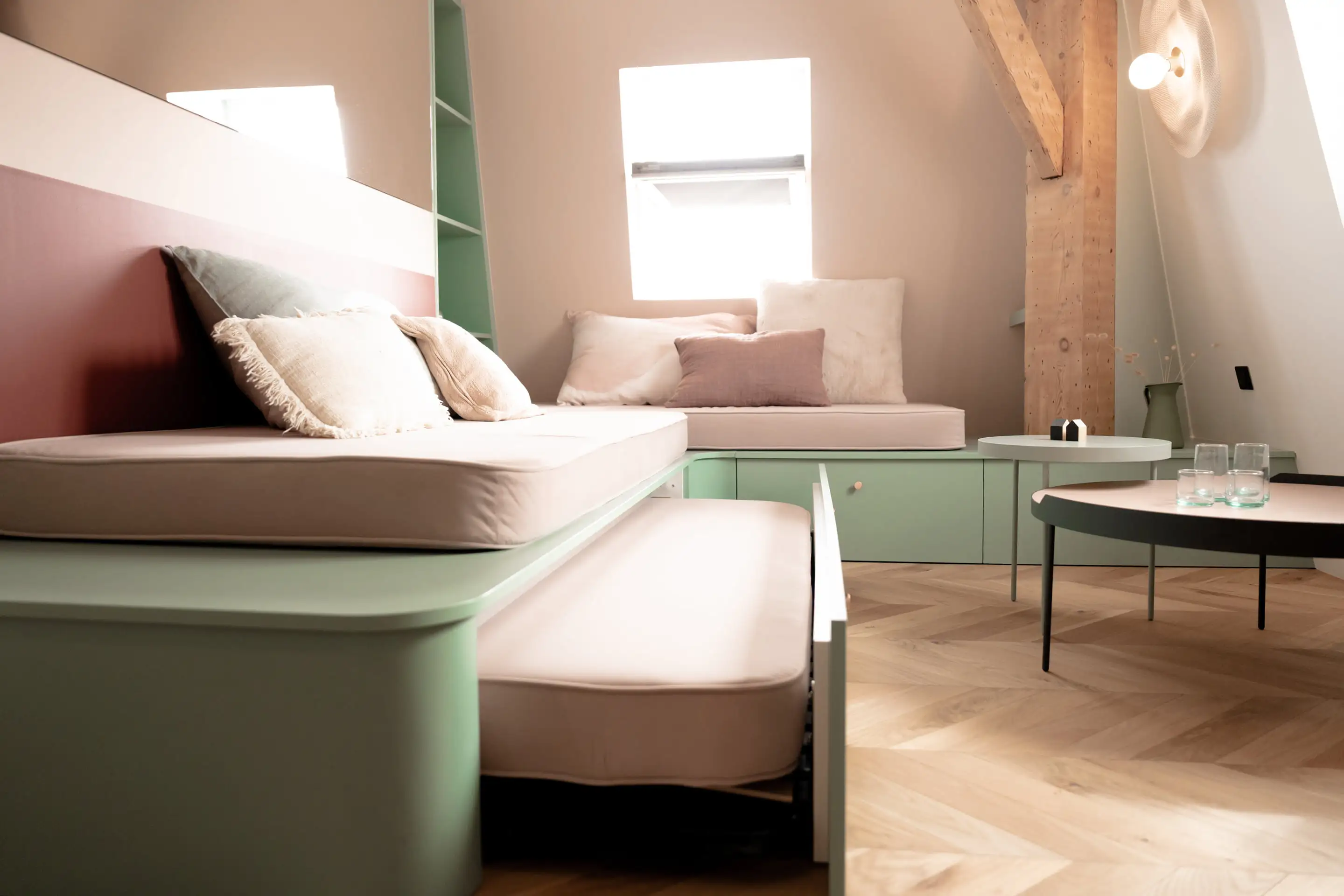 Banquette-lit sur mesure et table basse noire sur le parquet en point de Hongrie