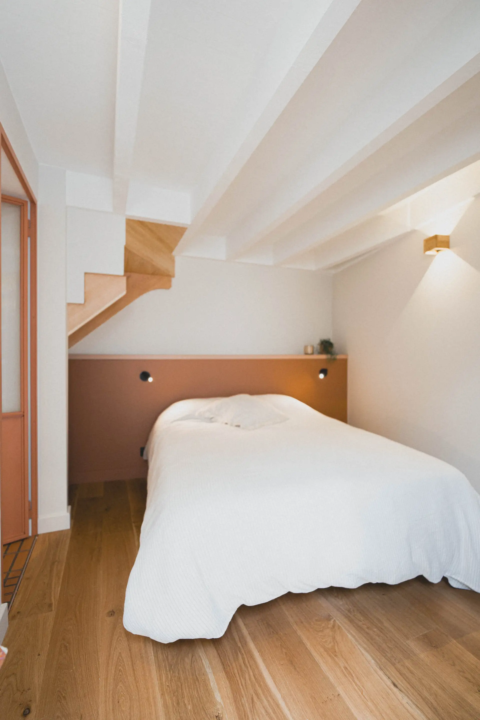 Chambre sous l’escalier, tête de lit couleur terre cuite et parquet en chêne