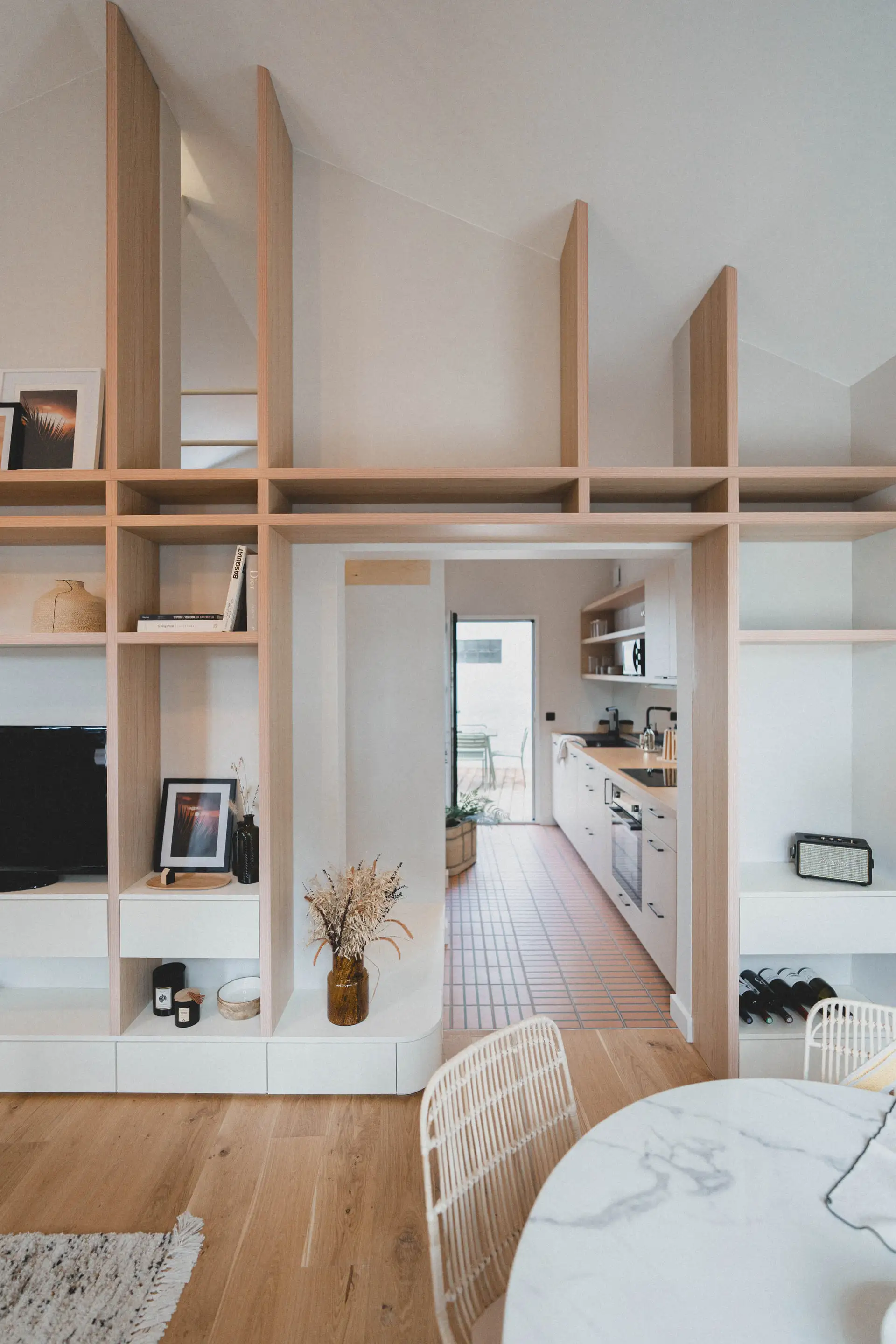 Bibliothèque sur mesure en bois clair, ouverte sur la cuisine en enfilade