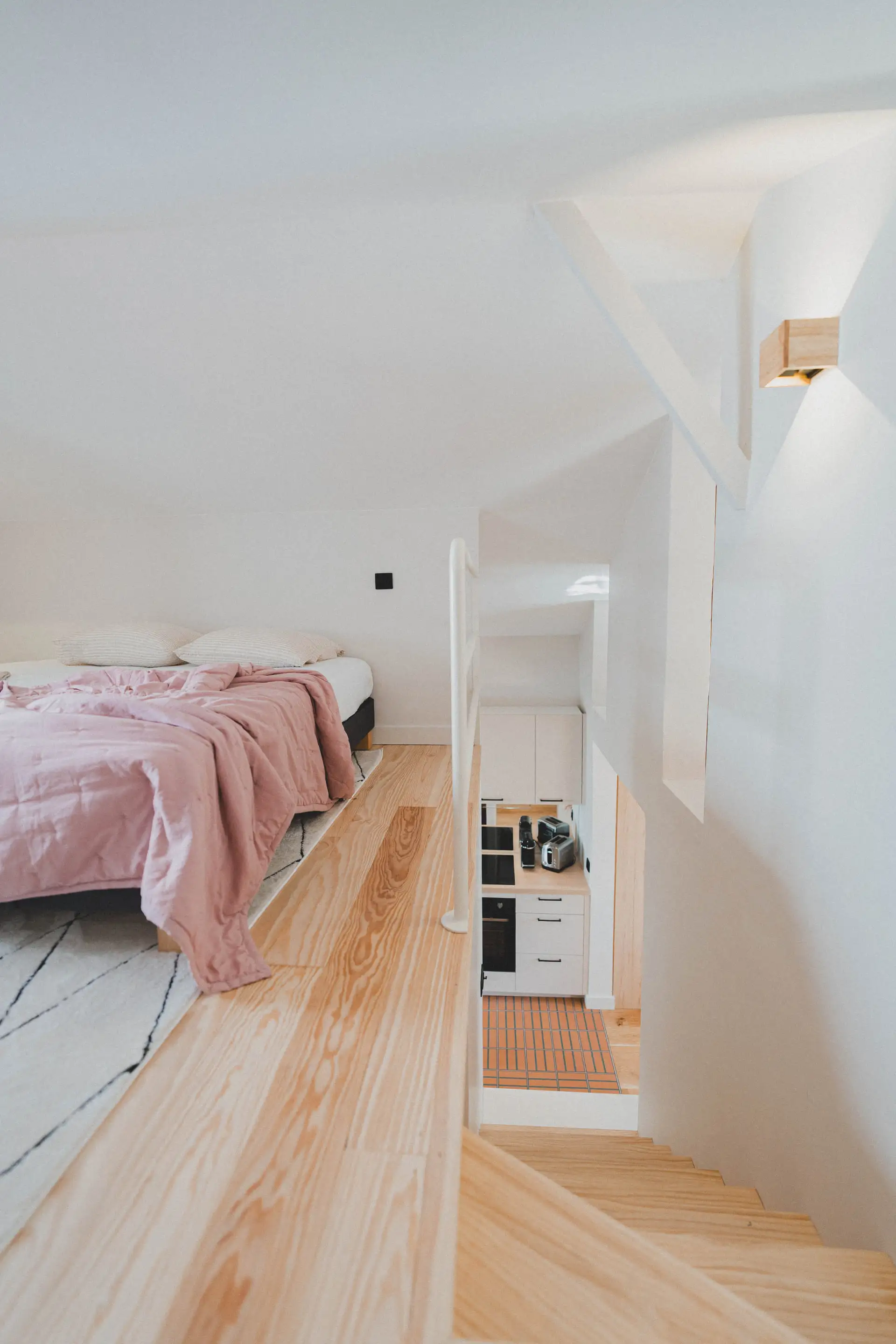 Chambre en mezzanine sous le toit, couvre-lit rose et parquet clair