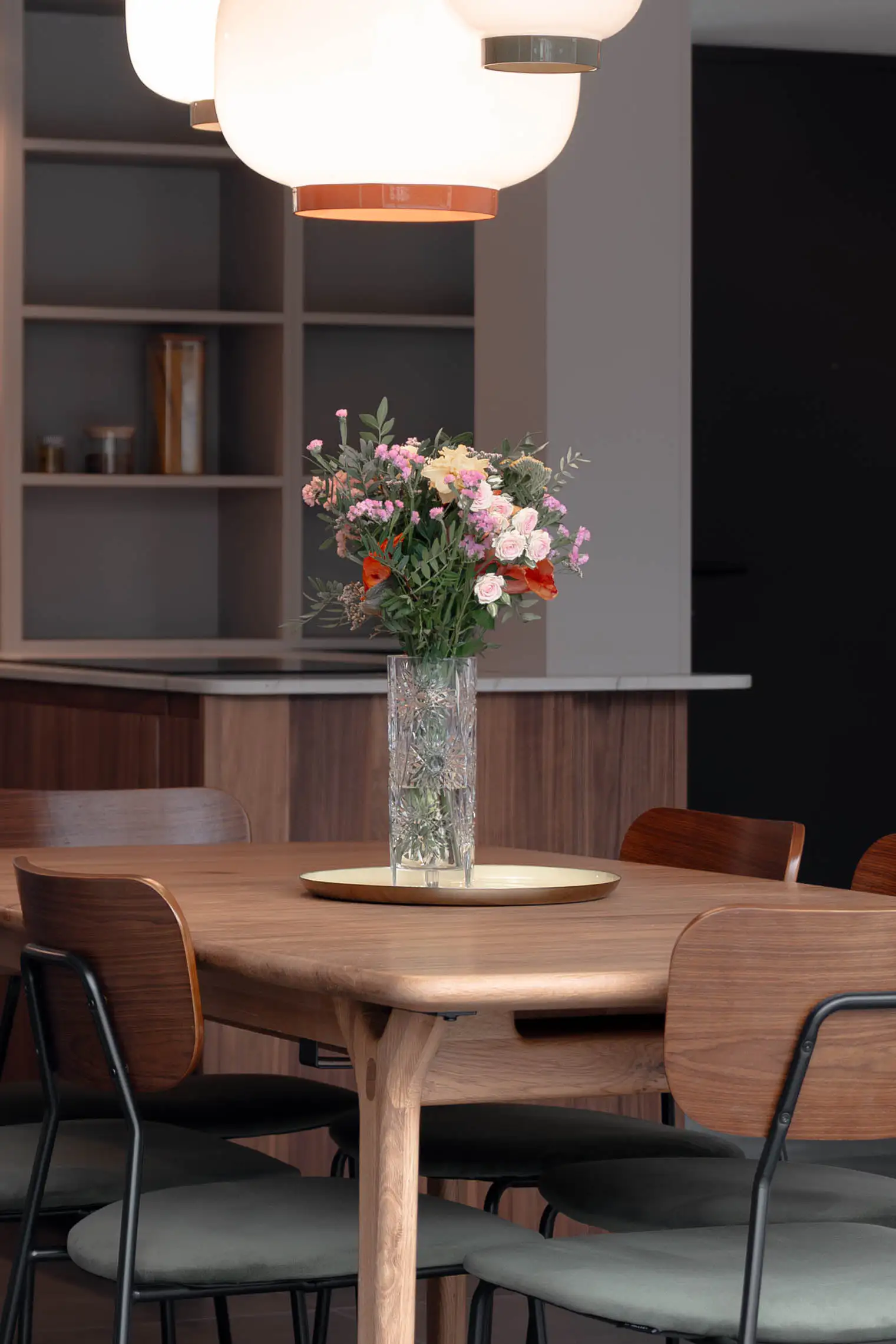 Table en bois dressée sous une suspension, bouquet et bibliothèque ouverte