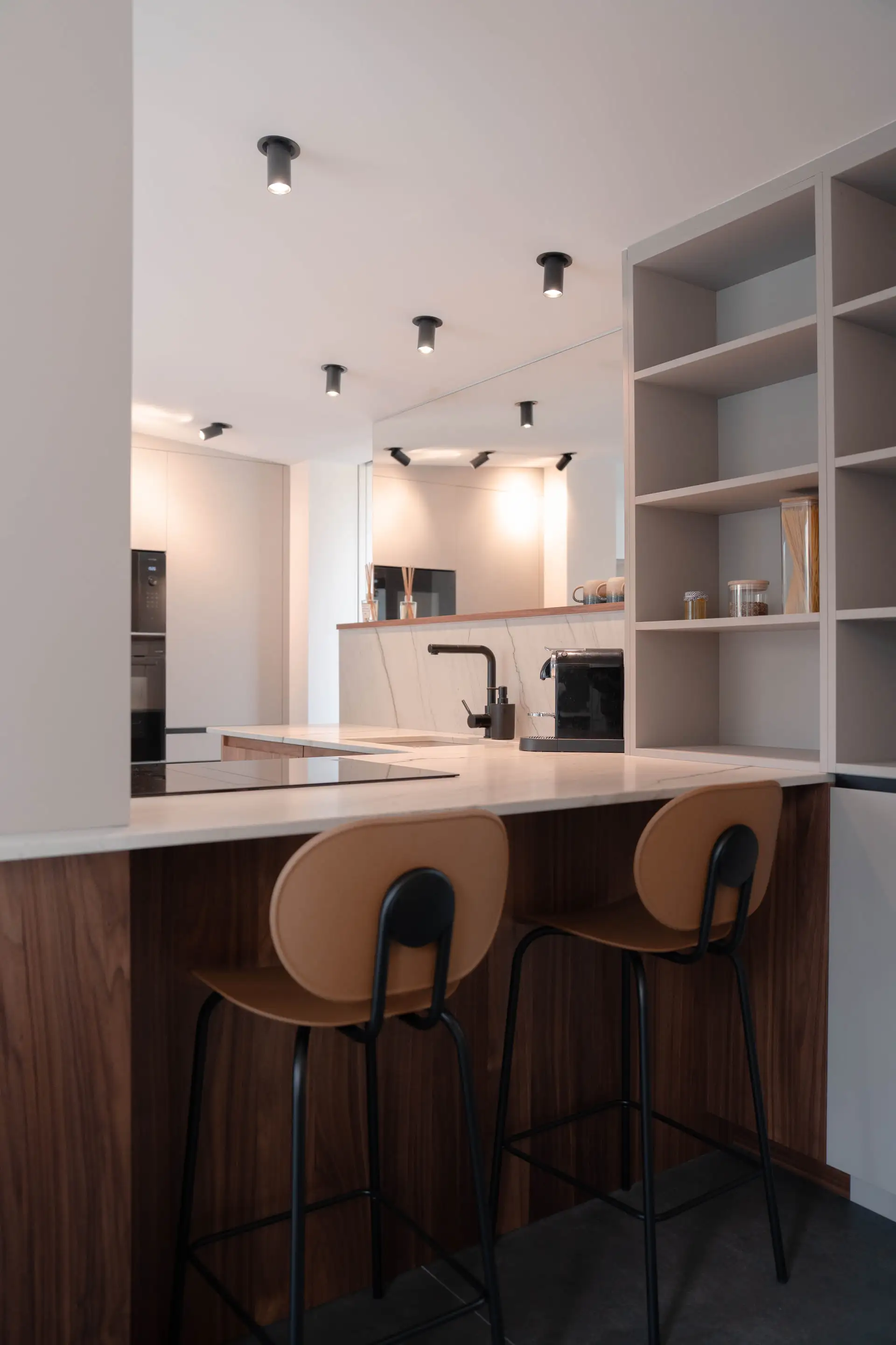 Cuisine sobre et îlot avec tabourets en bois, plafond à spots