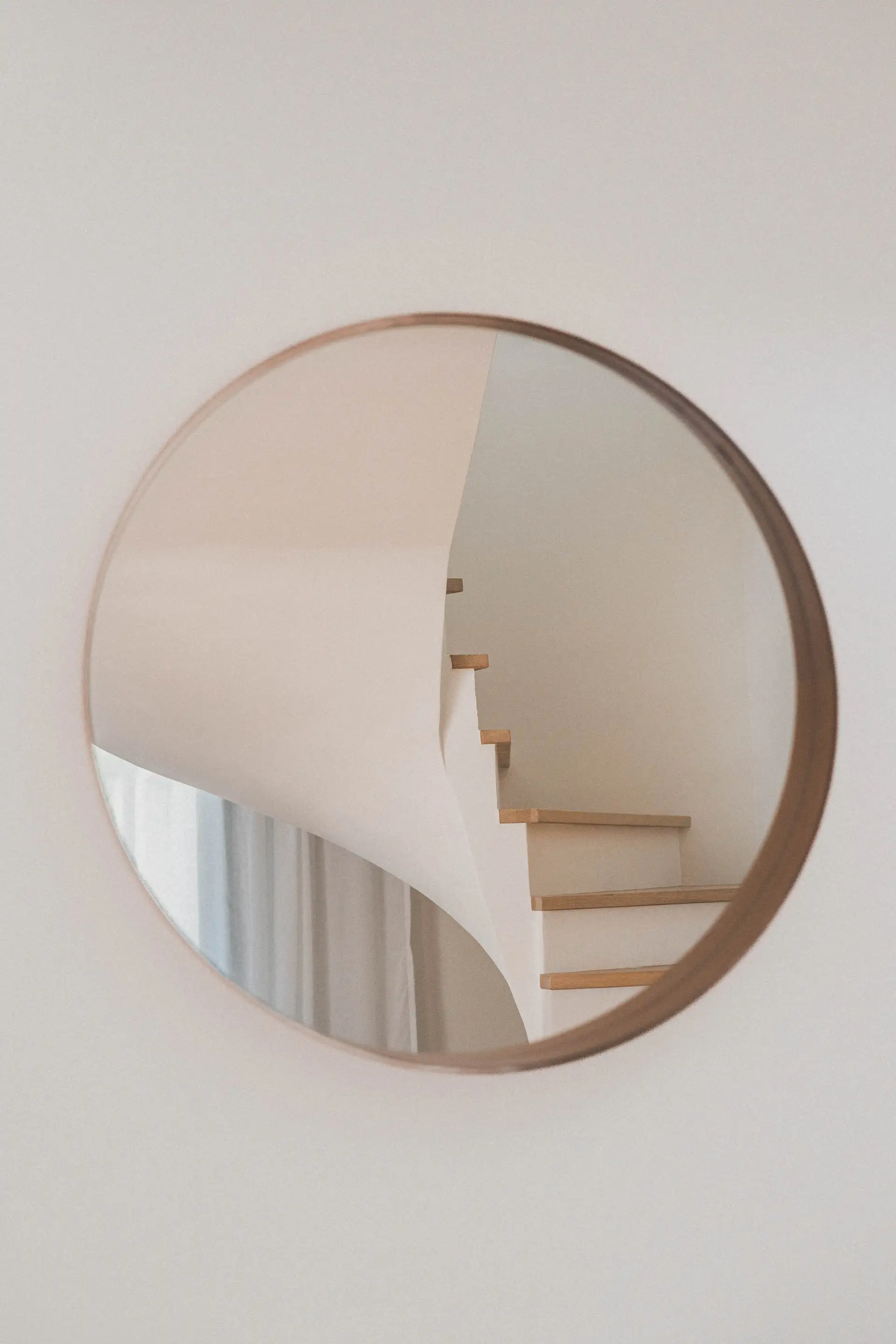 Miroir rond encadré de bois reflétant l’escalier