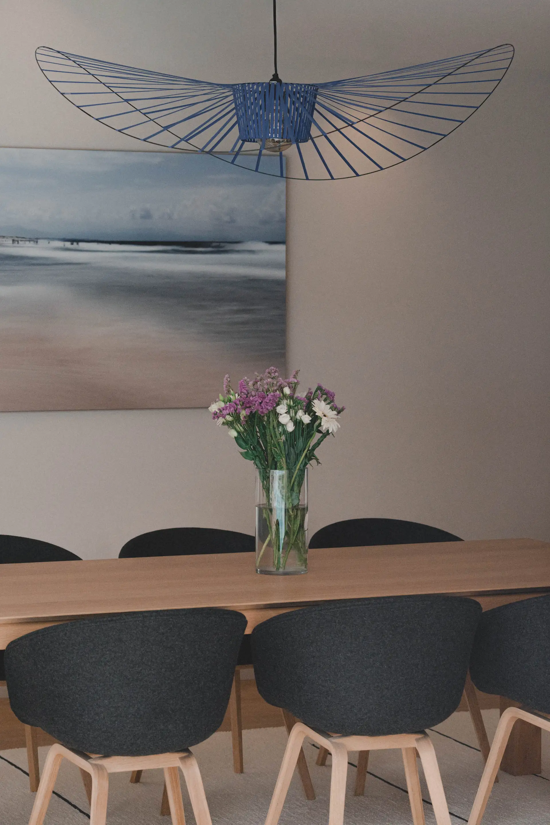 Table et chaises noires sous la suspension, tableau marin au mur
