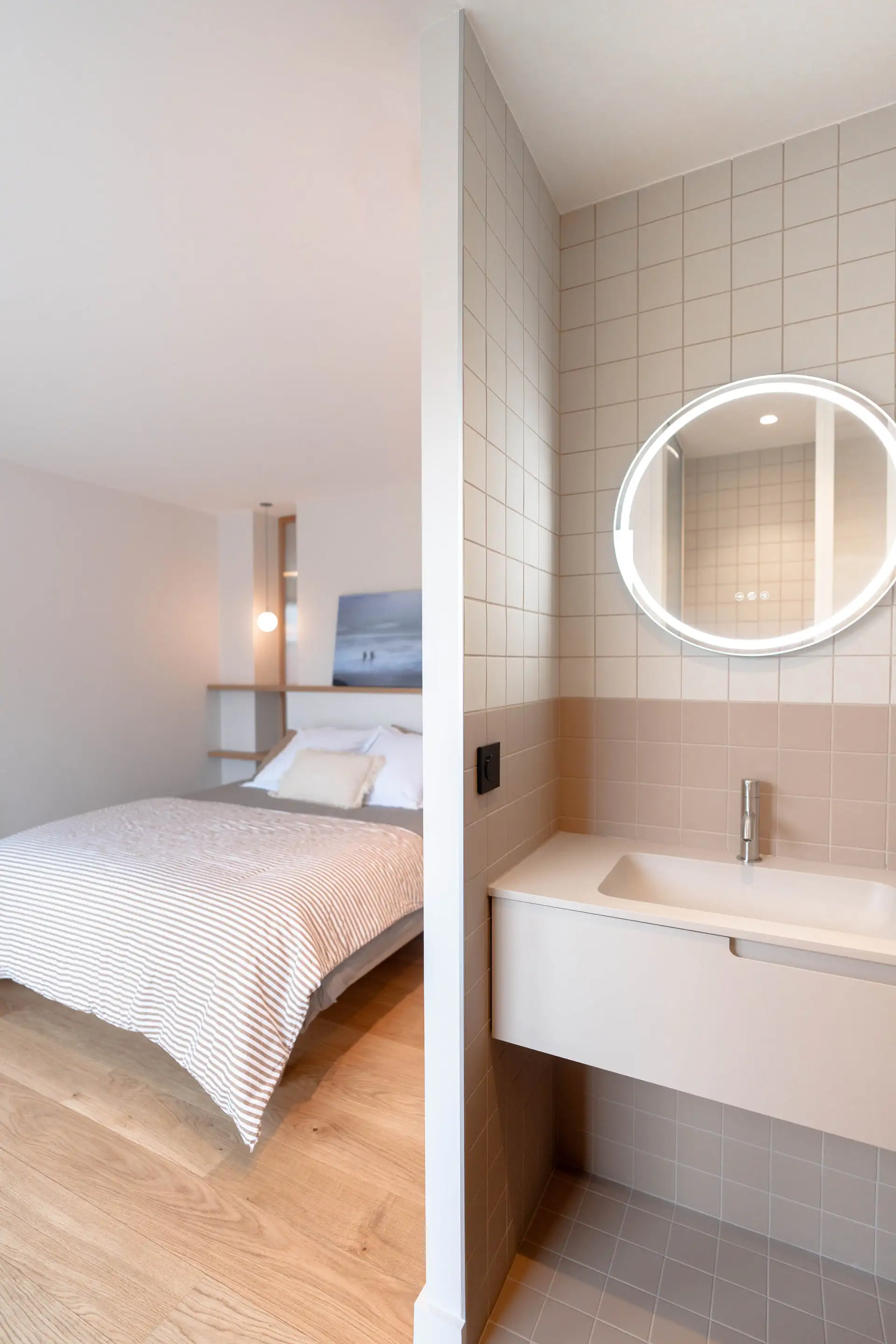 Chambre ouverte sur sa salle d’eau, miroir rond allumé