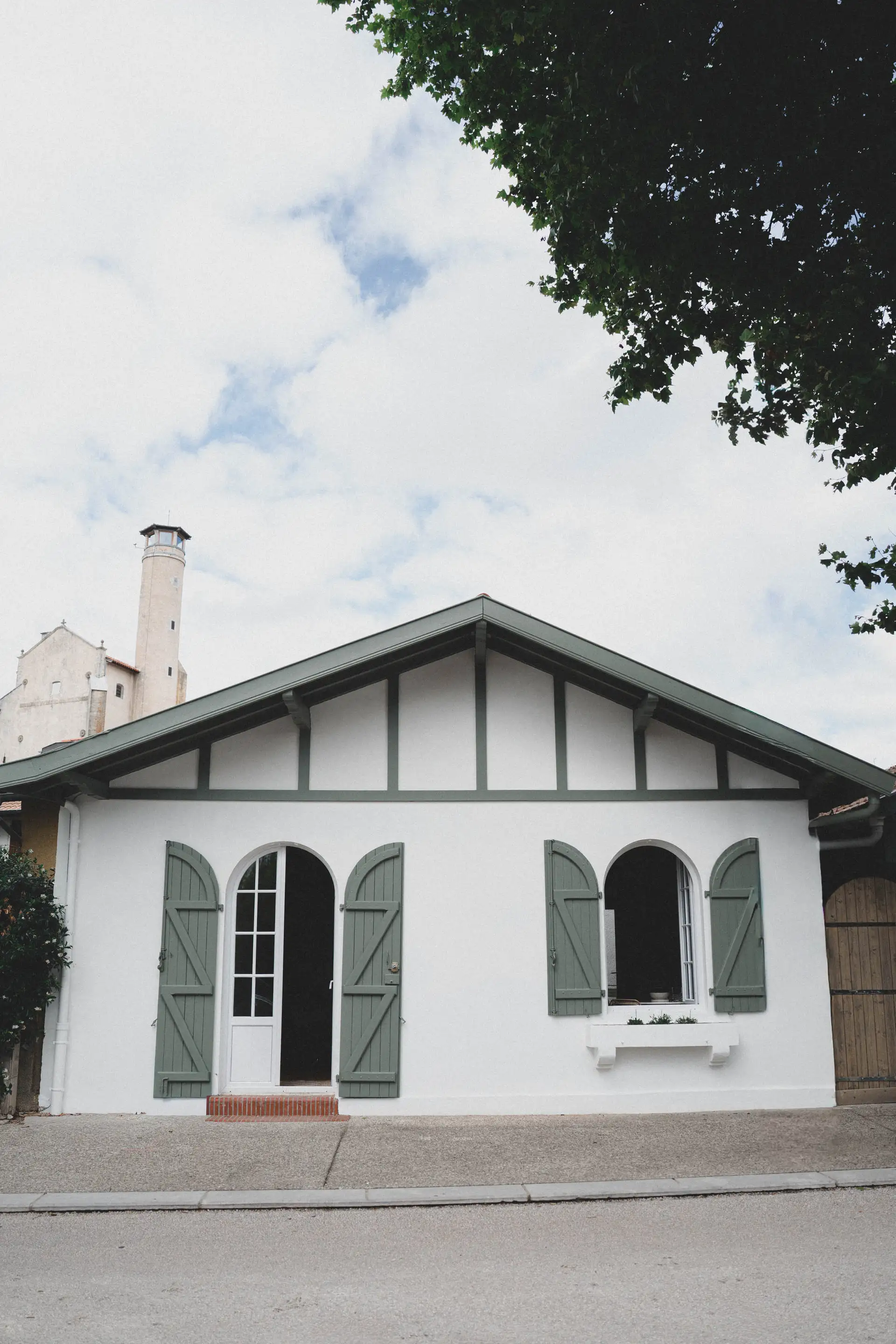 La maison vue de la rue, pignon à colombages et volets vert sauge