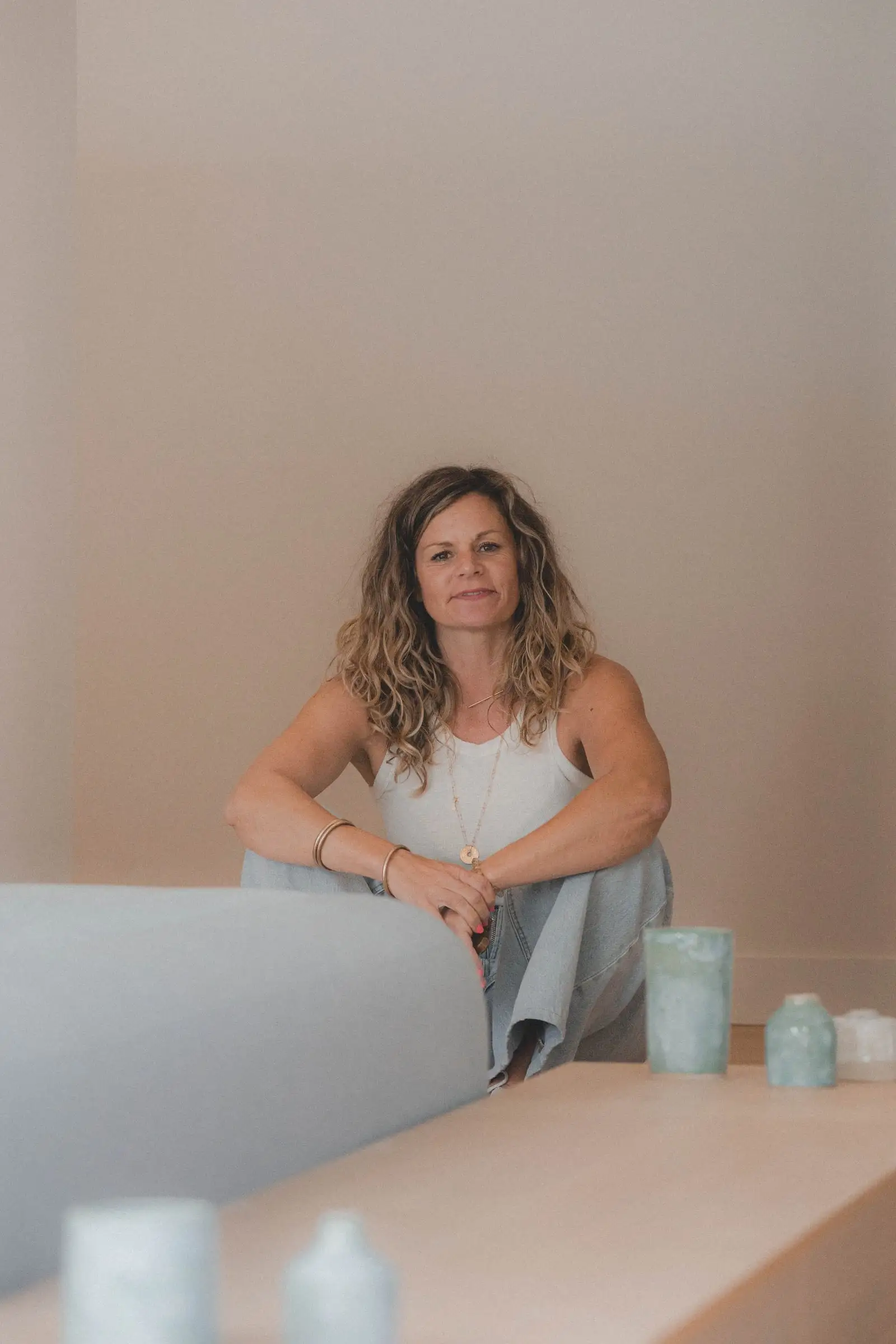 Émilie Barbé, assise, souriante, dans un intérieur aux tons rosés